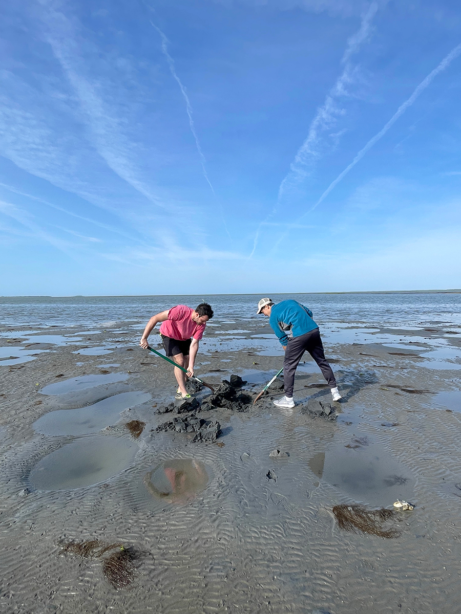 Undergrad Jonathan Moore and REU intern James Lu look for samples in a mud flat. © Grace Massey.