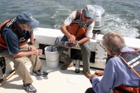 Ken Moore demonstrates his Dataflow monitoring gear during a visit by W&M President Taylor Reveley. From L: VIMS Dean & Director John Wells, Moore, and Reveley.